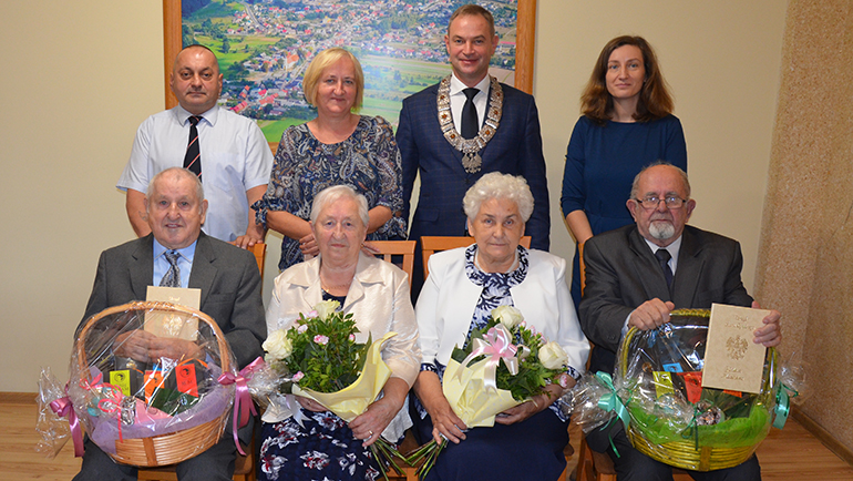 alt="Od lewej u dołu Państwo Zygmunt i Edyta Szopińscy, Państwo Maria i Stanisław Trycowie. U góry od lewej zięć z córką Państwa Szopińskich, Wójt Daniel Kożuch, Zastępca Kierownika USC Anna Pril"