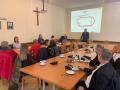 uczestnicy podczas spotkania odnośnie nowego stadionu, w tle projekt