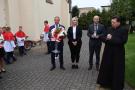 Wójt i przedstawiciele gminy stoją z bukietem kwiatów
