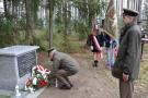 wojskowy składa bukiet kwiatów pod pomnikiem