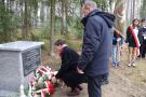 kobieta składa bukiet kwiatów pod pomnikiem