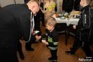 chłopiec w stroju strażaka dzieli się opłatkiem z mężczyzną