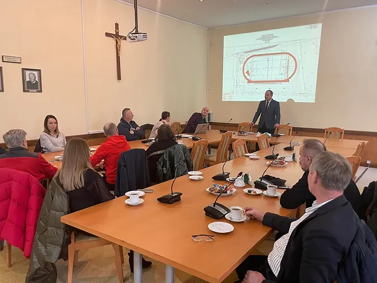 uczestnicy podczas spotkania odnośnie nowego stadionu, w tle projekt