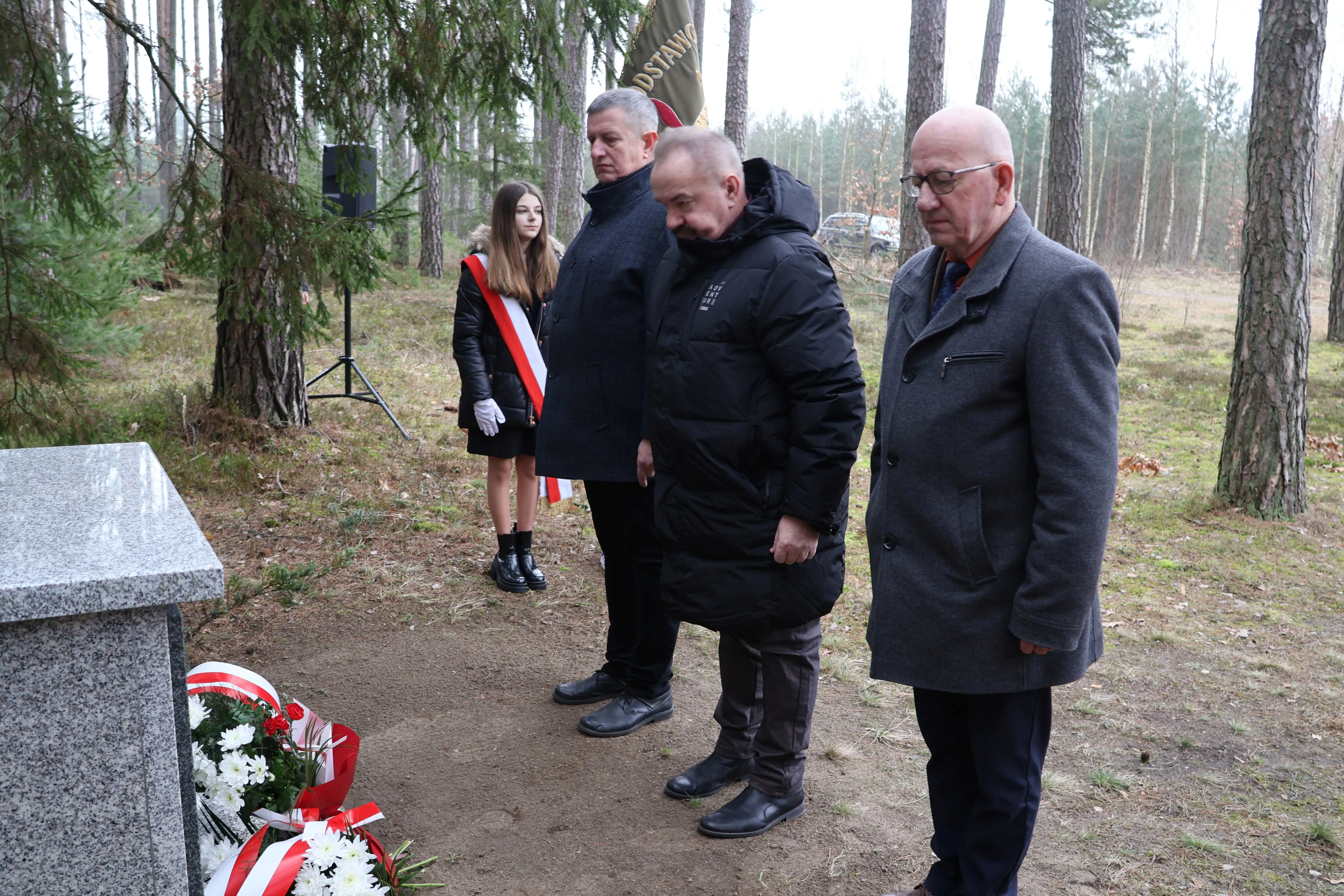 trzech mężczyzn stoi przed pomnikiem