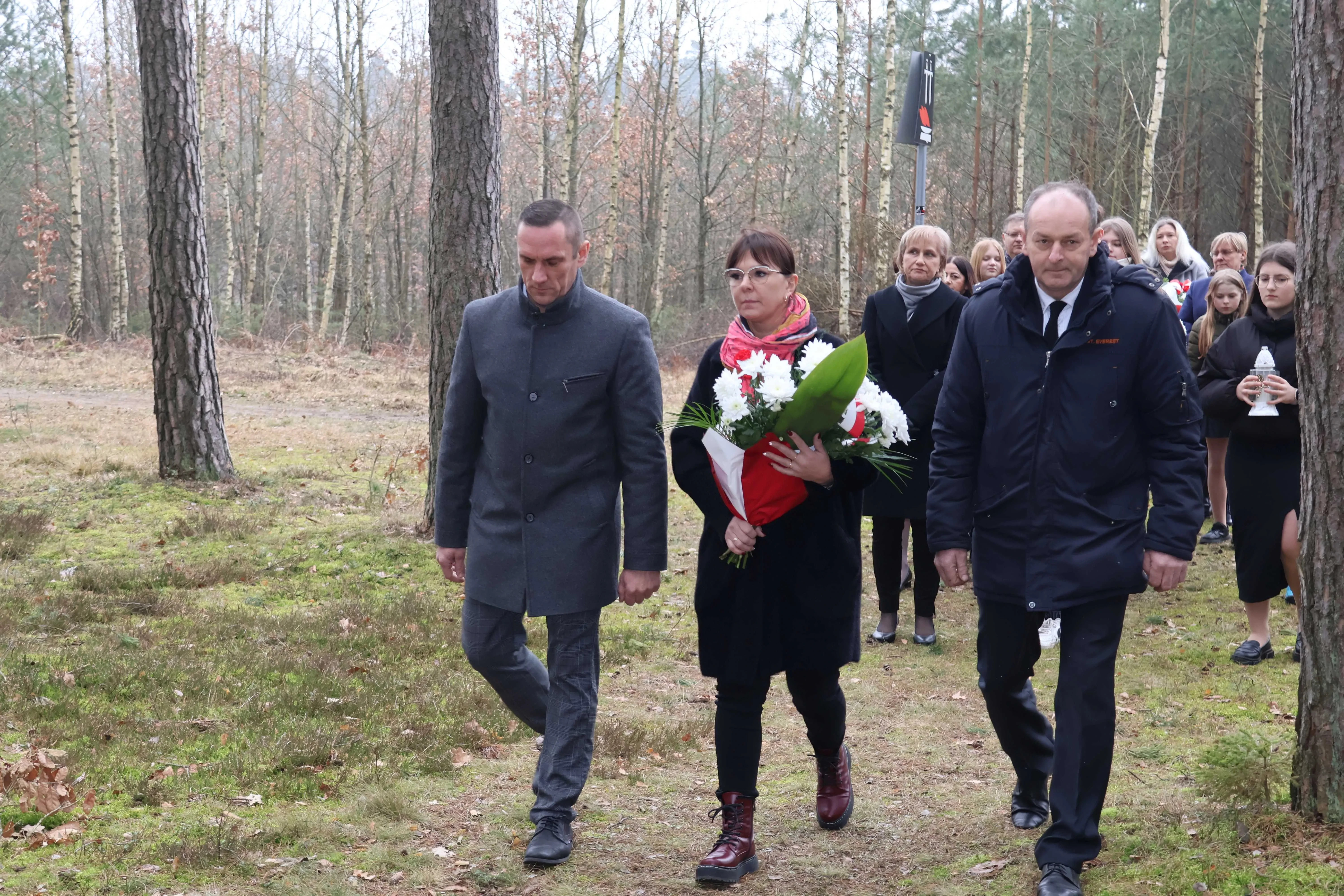 kobieta trzymająca bukiet kwiatów między dwoma mężczyznami