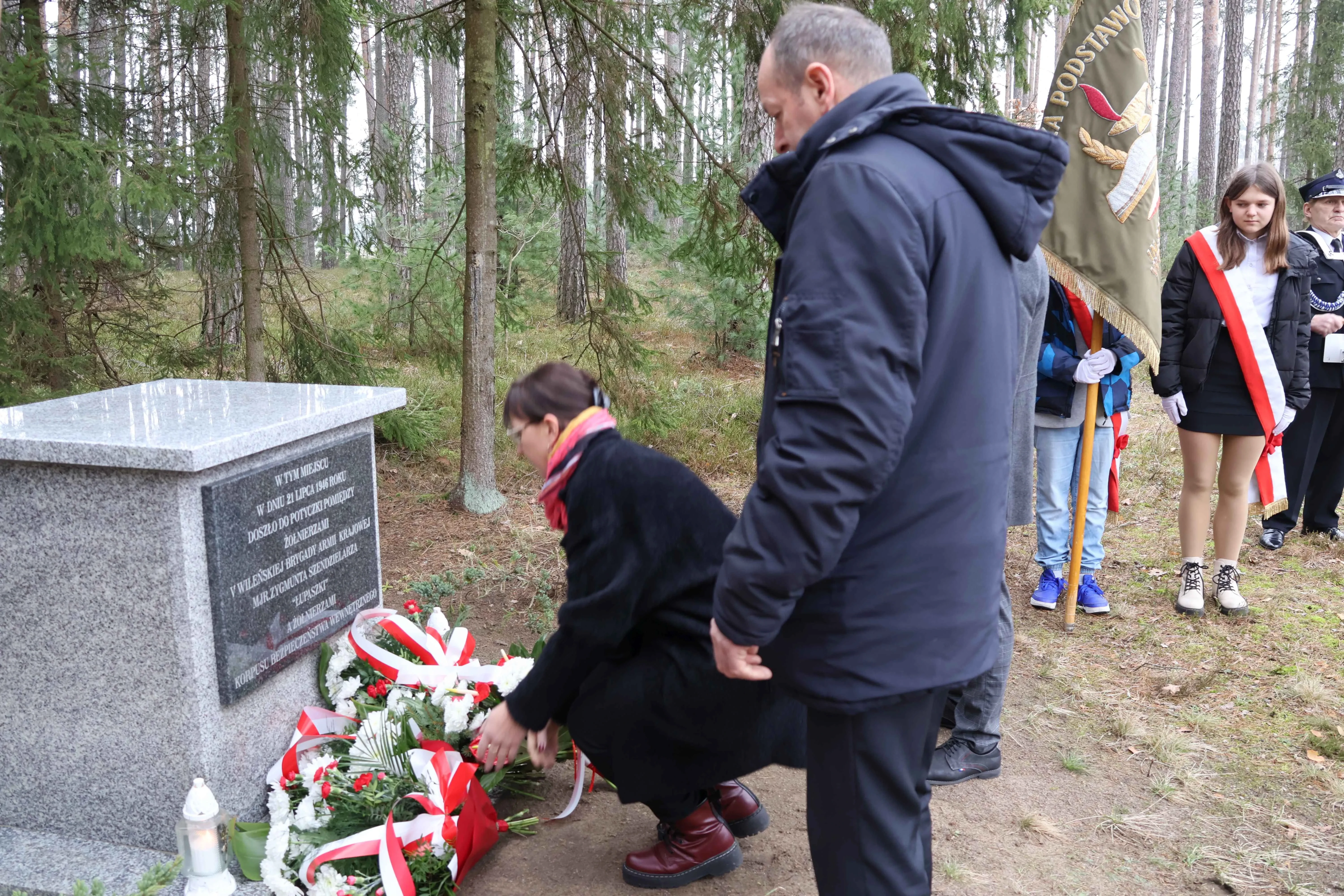 kobieta składa bukiet kwiatów pod pomnikiem