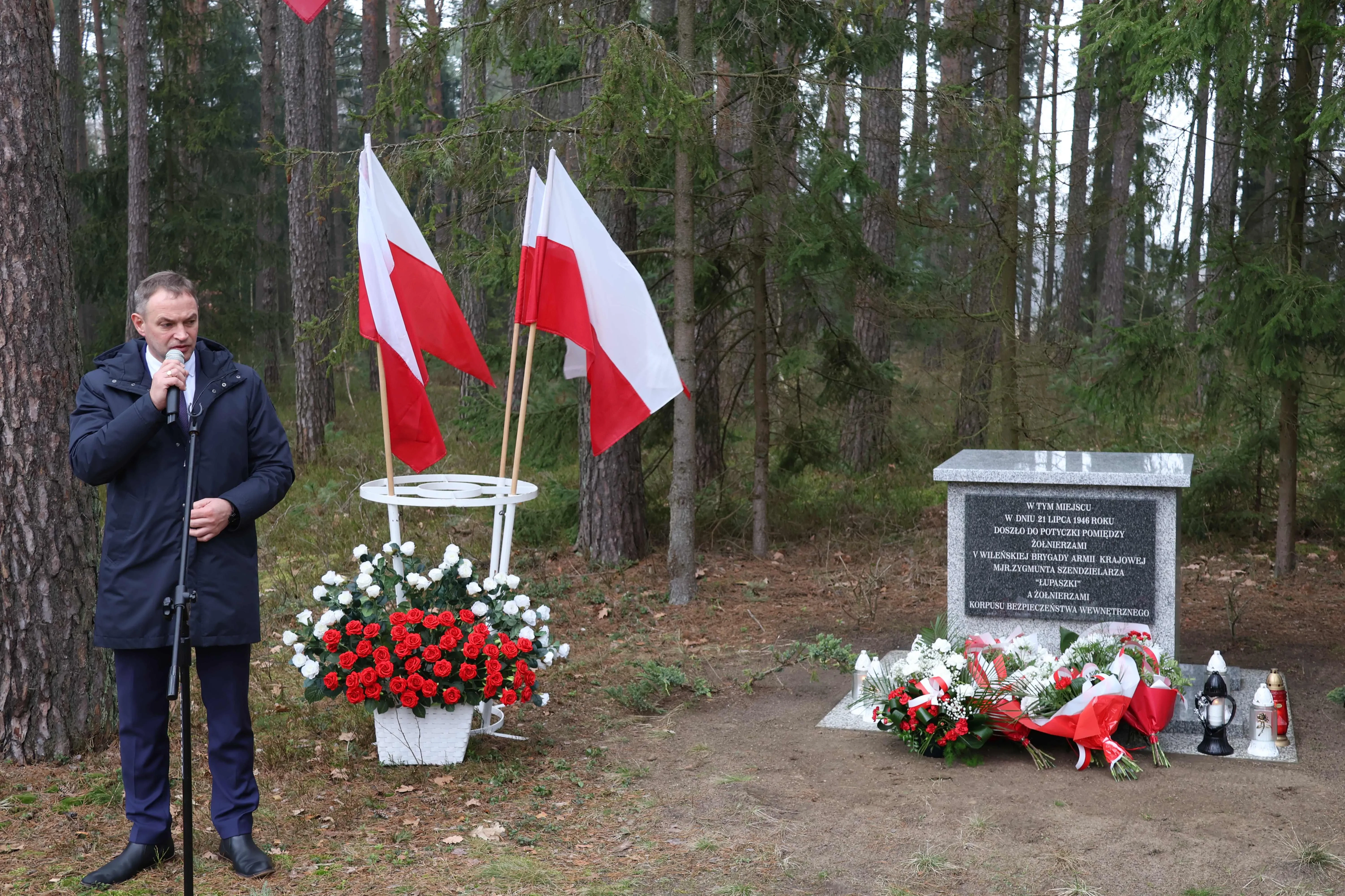 wójt stoi obok dwóch pomników żołnierzy wyklętych