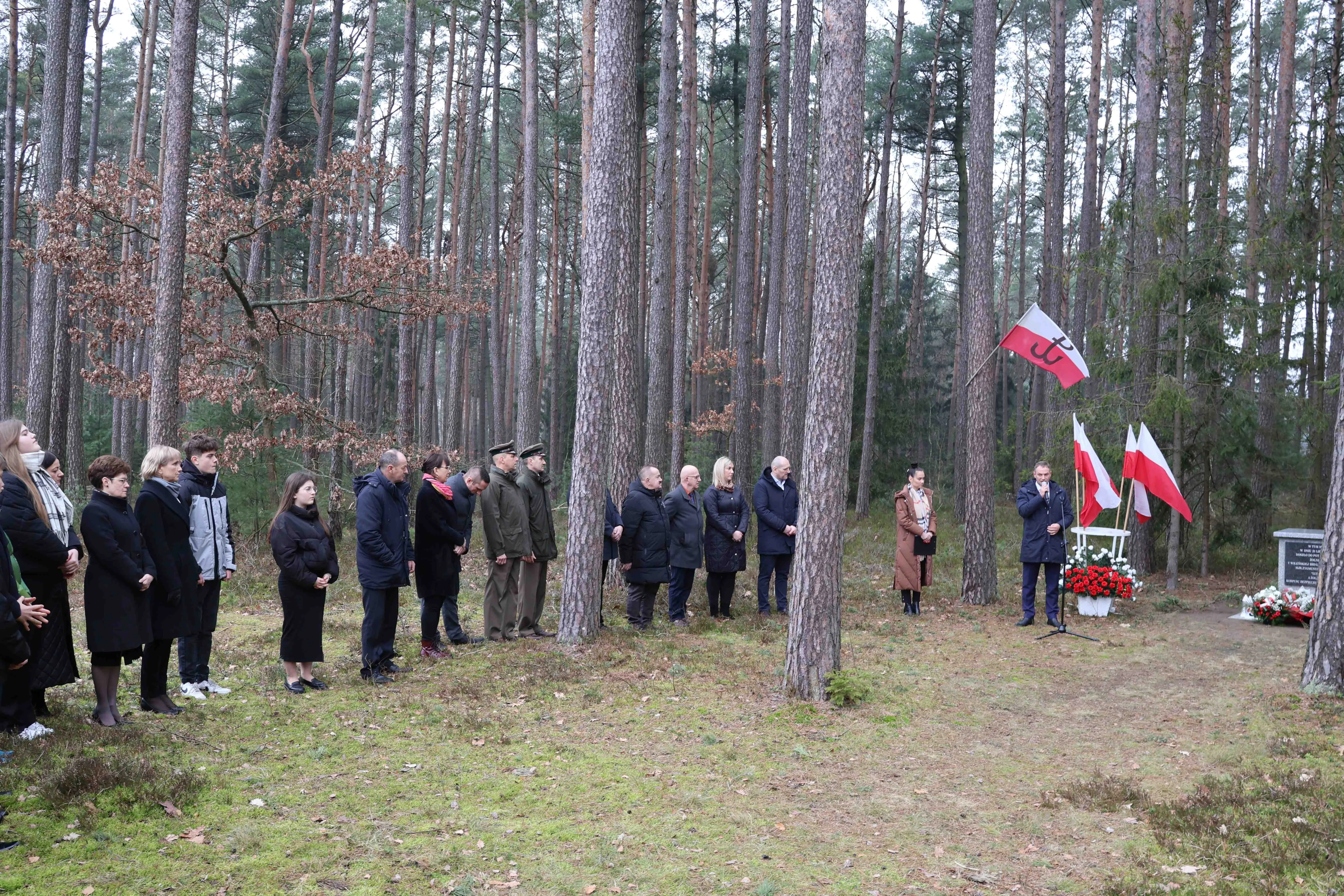 ludzie stojący w lesie na tle dwóch pomników