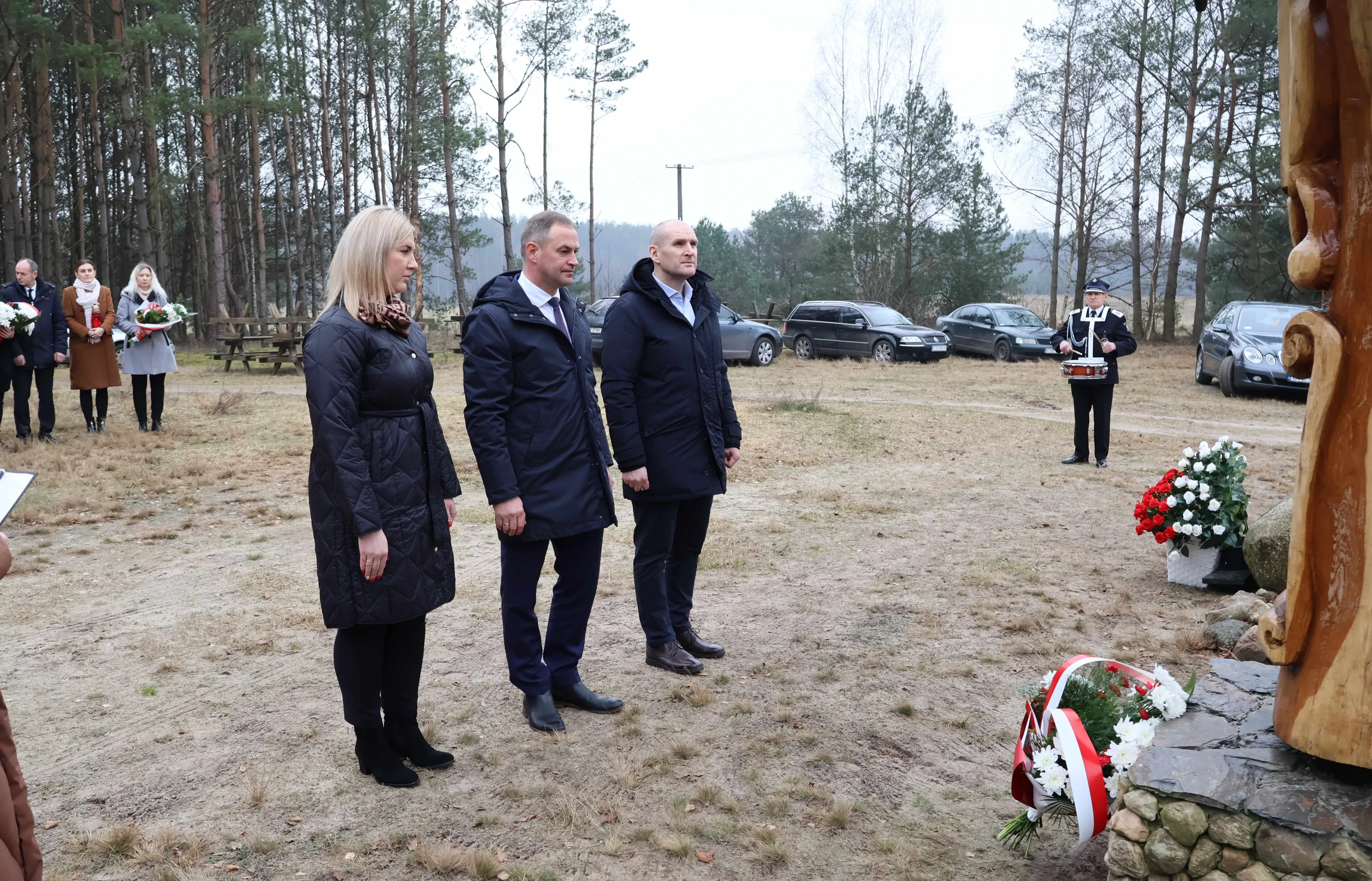 dwóch mężczyzn i kobieta stoją przed pomnikiem