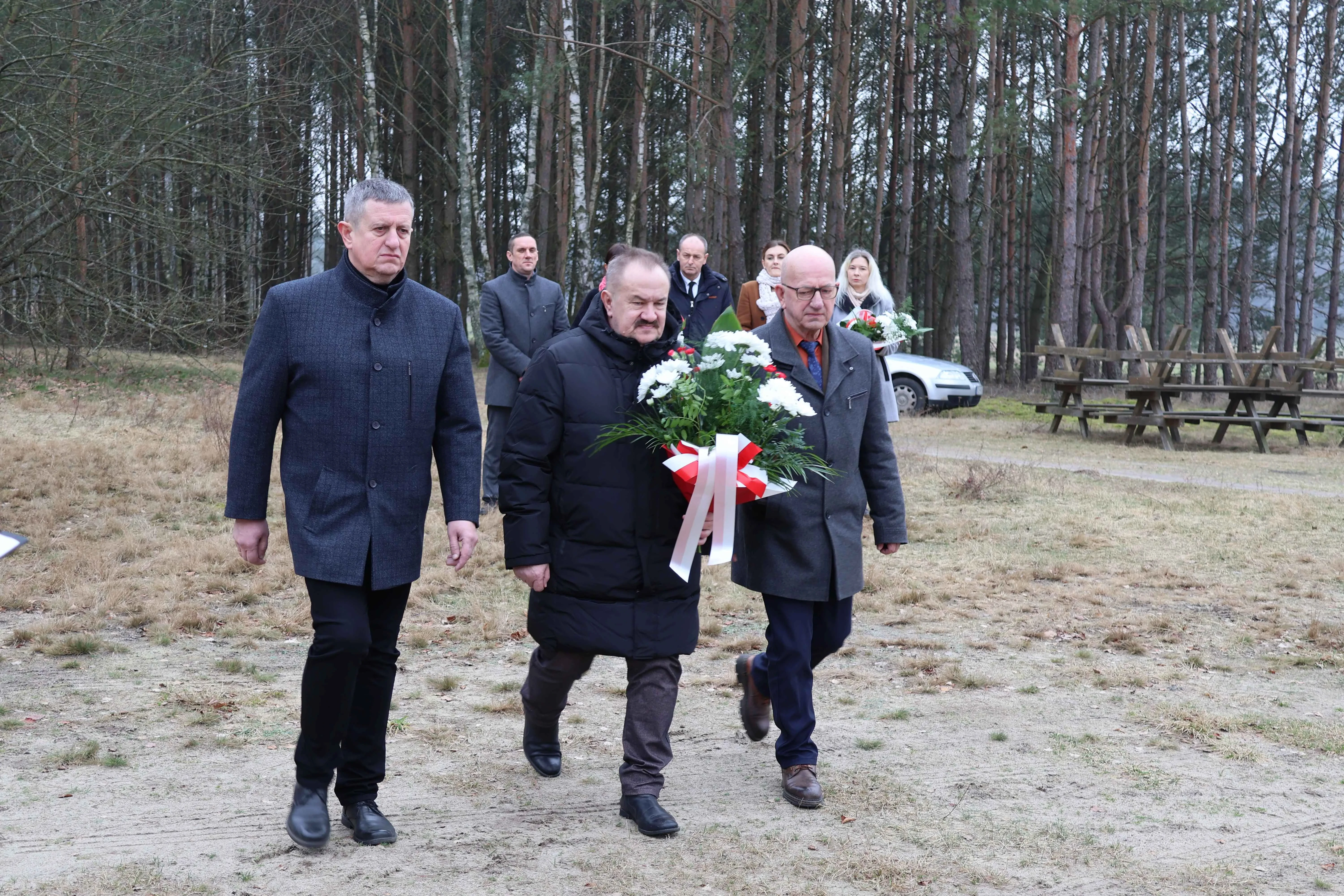 trzech mężczyzn idzie pod pomnik