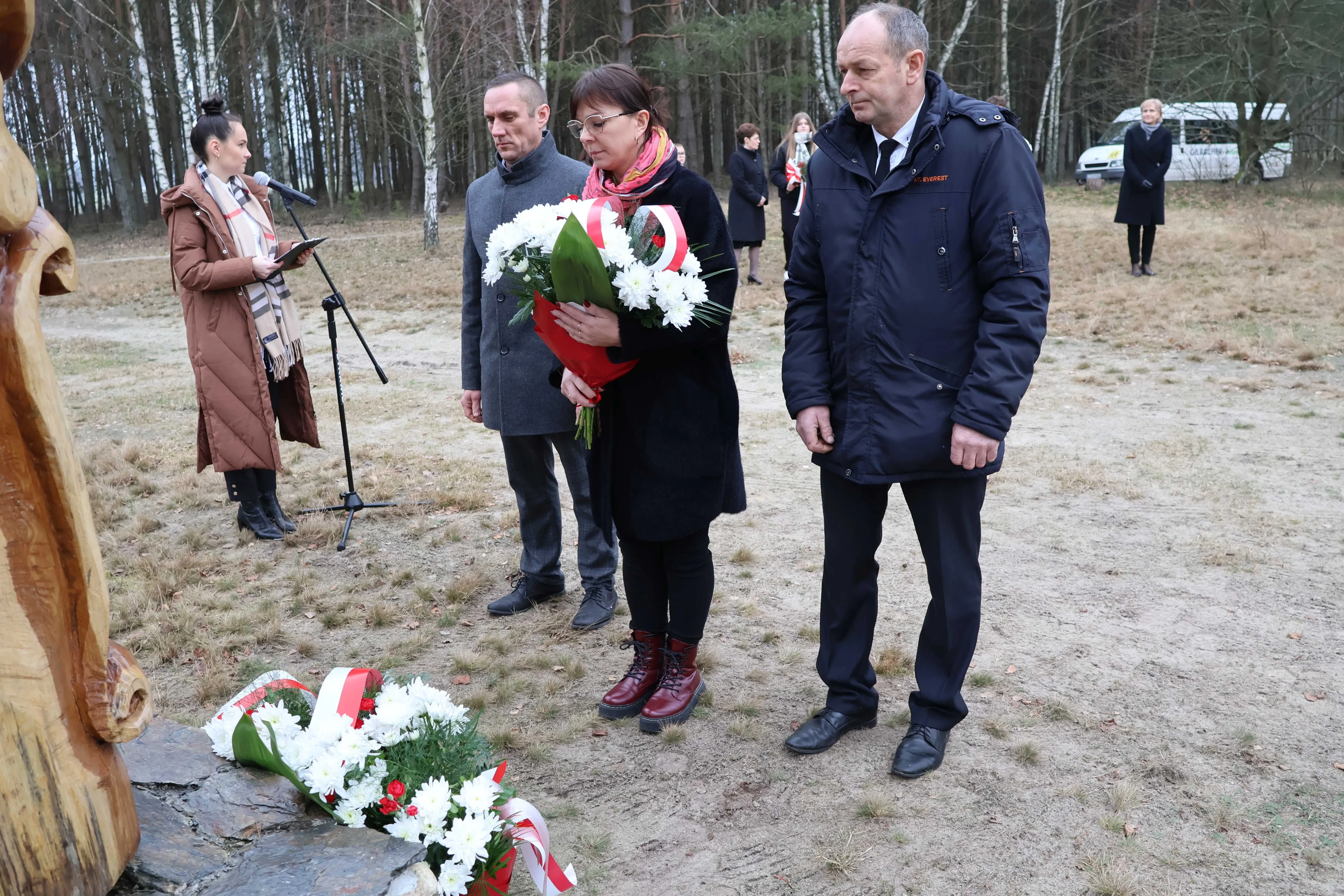 dwóch mężczyzn i kobieta stoją przed pomnikiem