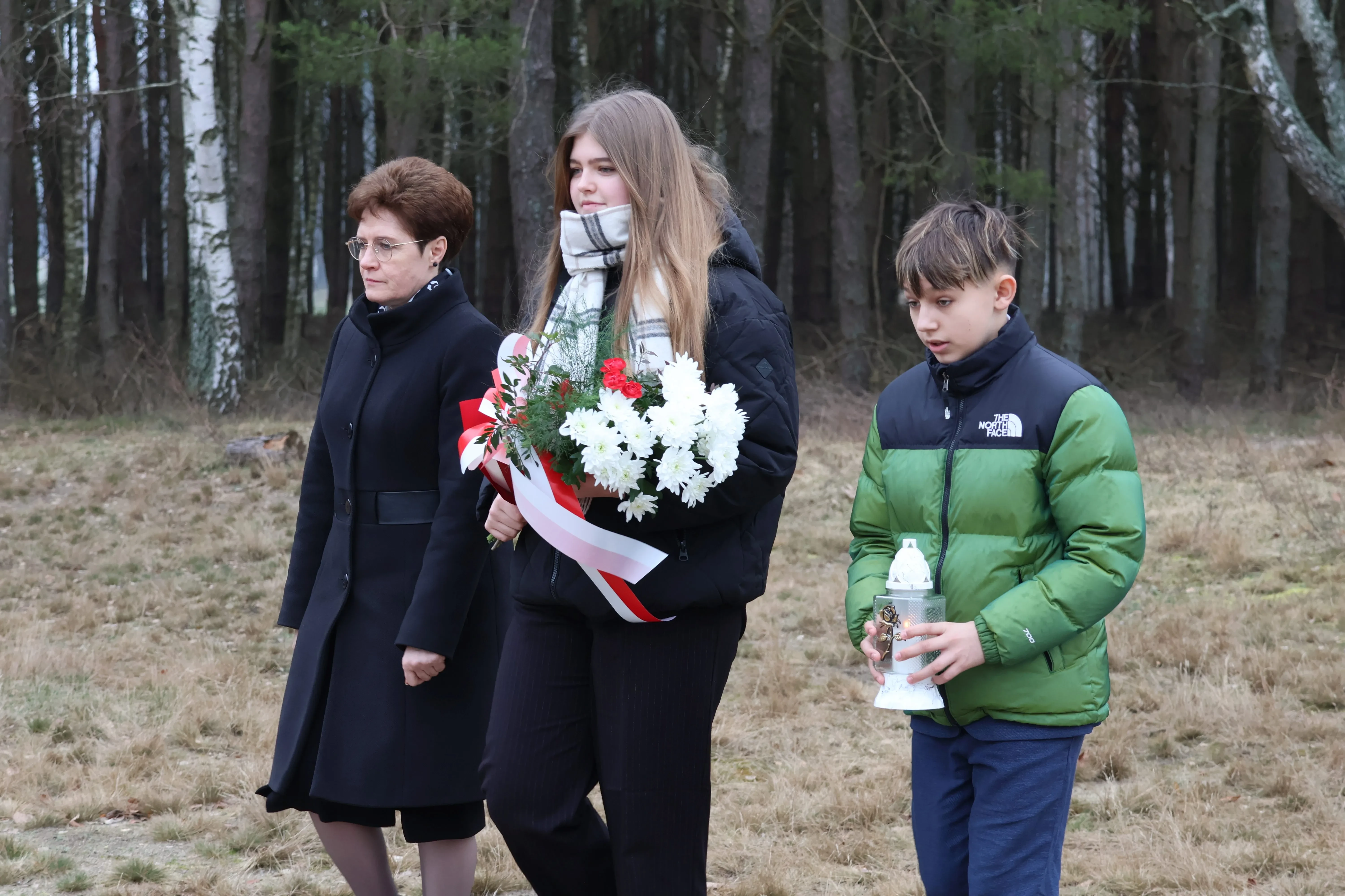 trójka dzieci trzymająca wieniec kwiatów