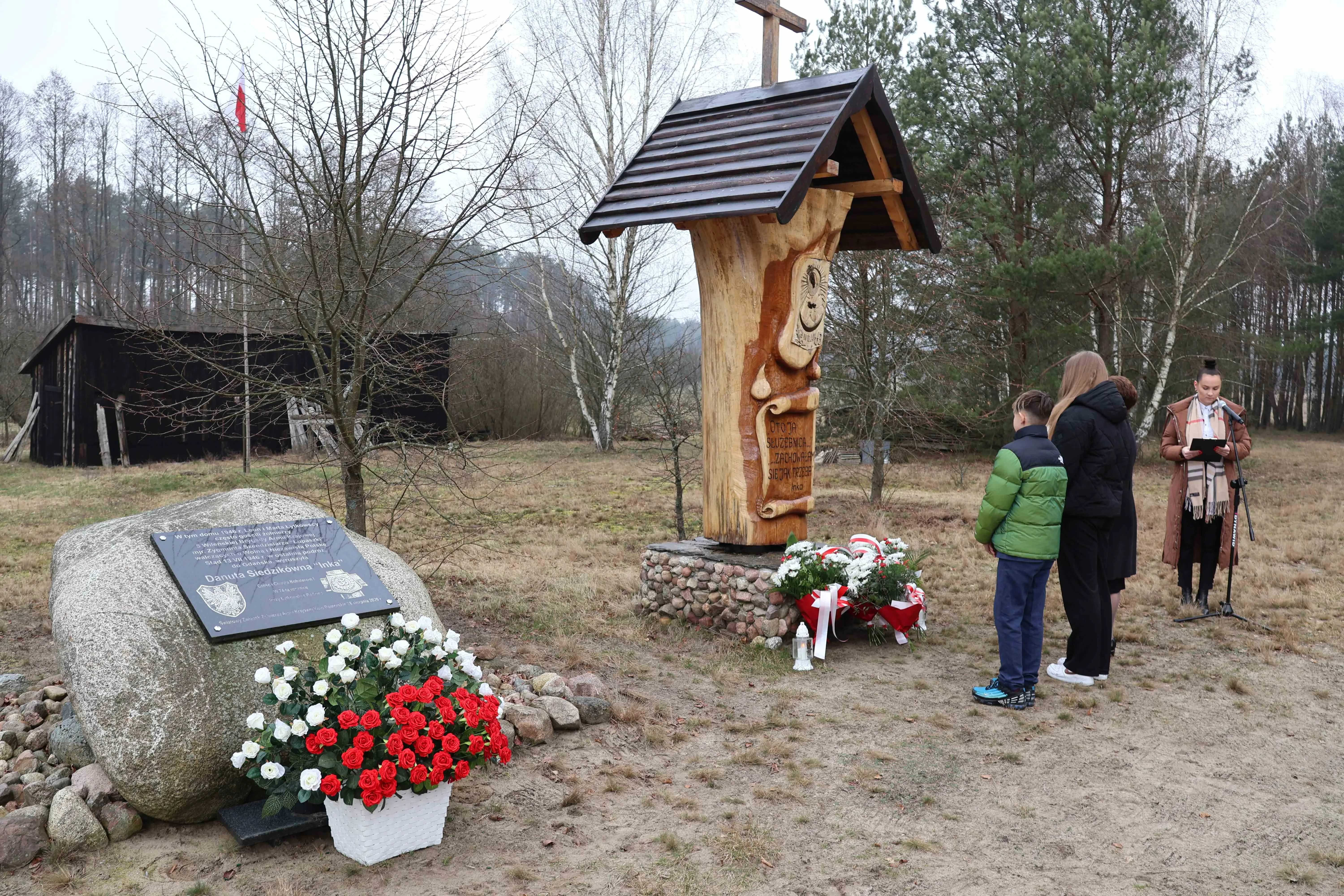 grupka dzieci stojąca przy pomniku żołnierzy wyklętych
