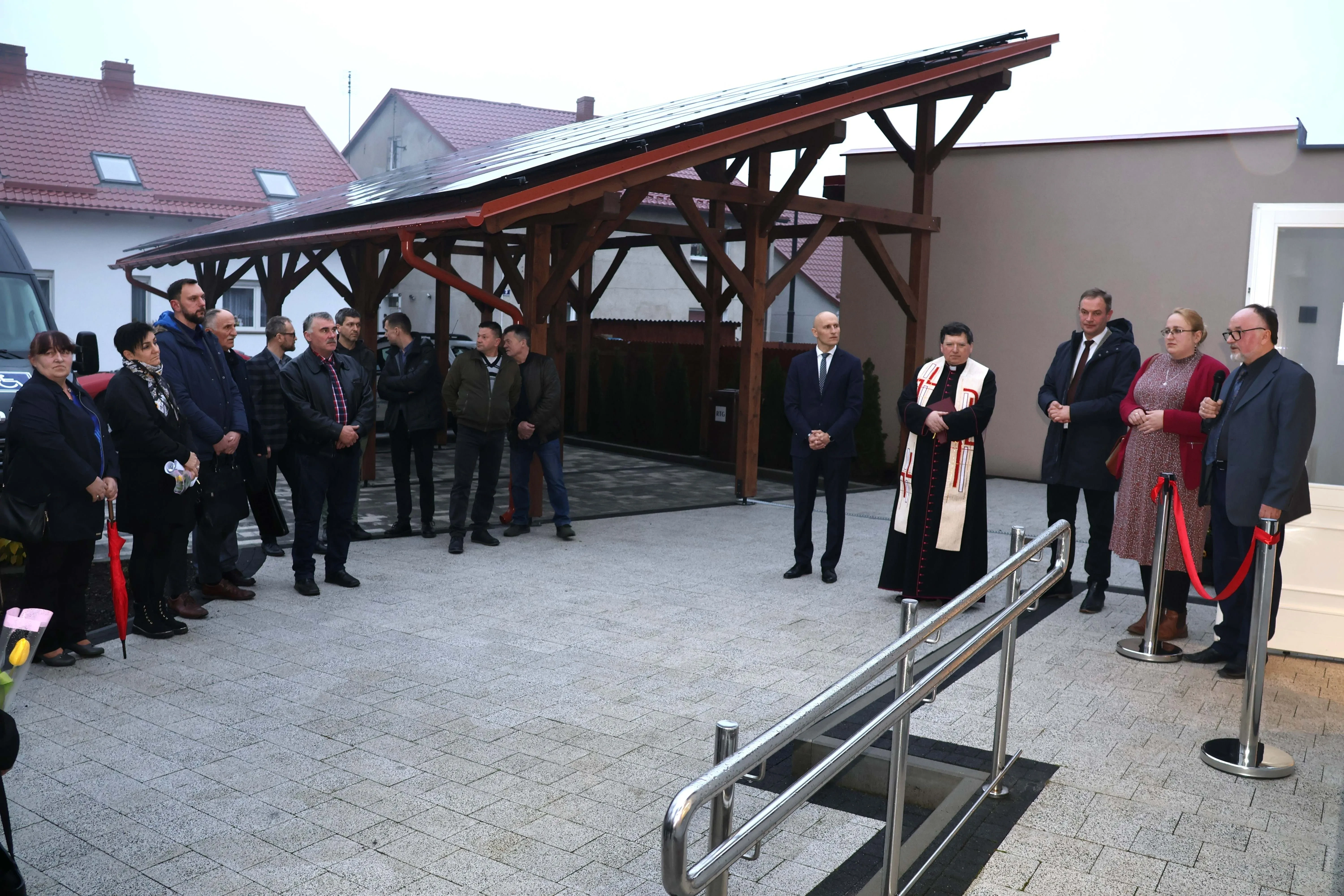 grupa ludzi i ksiądz przed przychodnią
