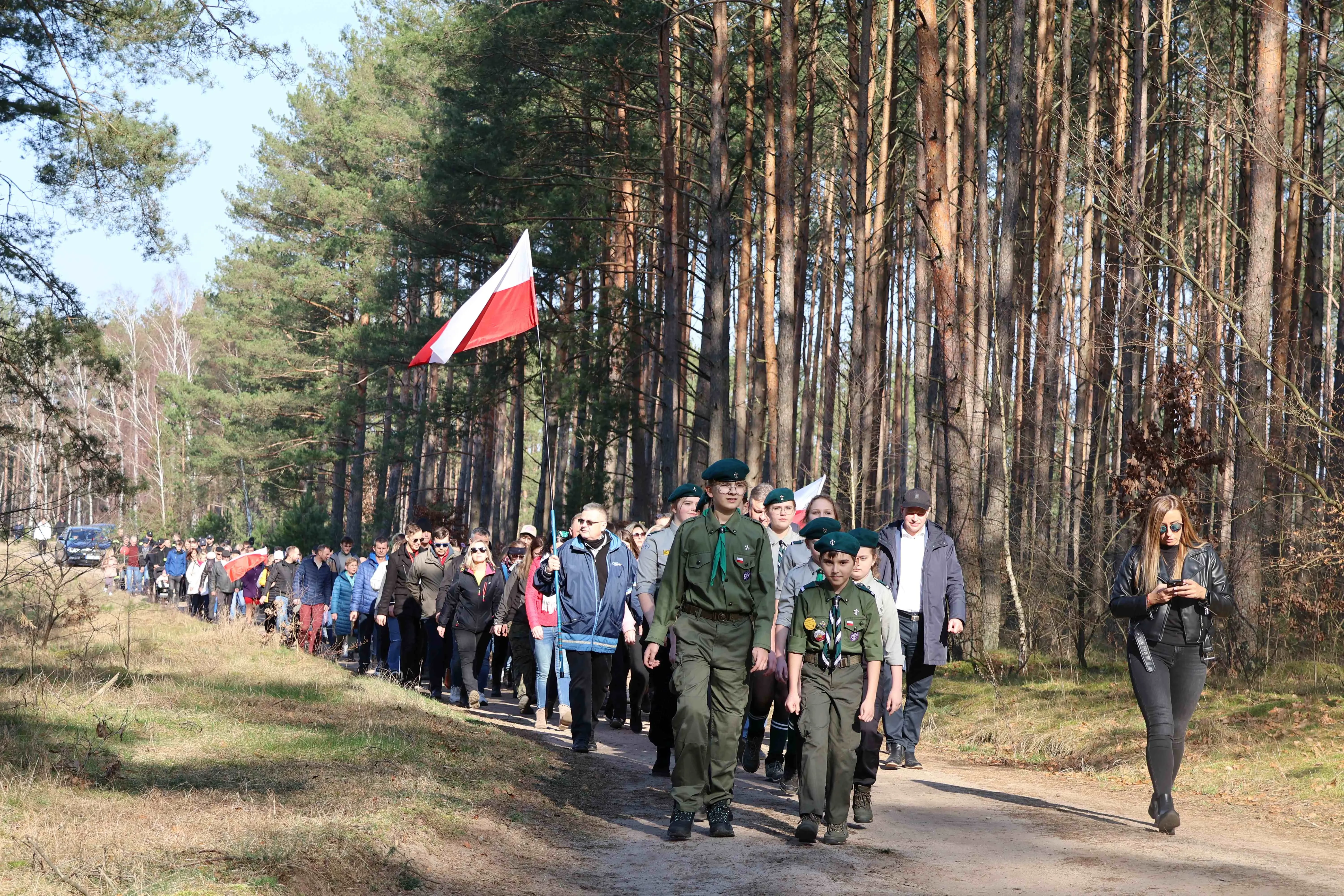 harcerze prowadzą grupę ludzi przez las