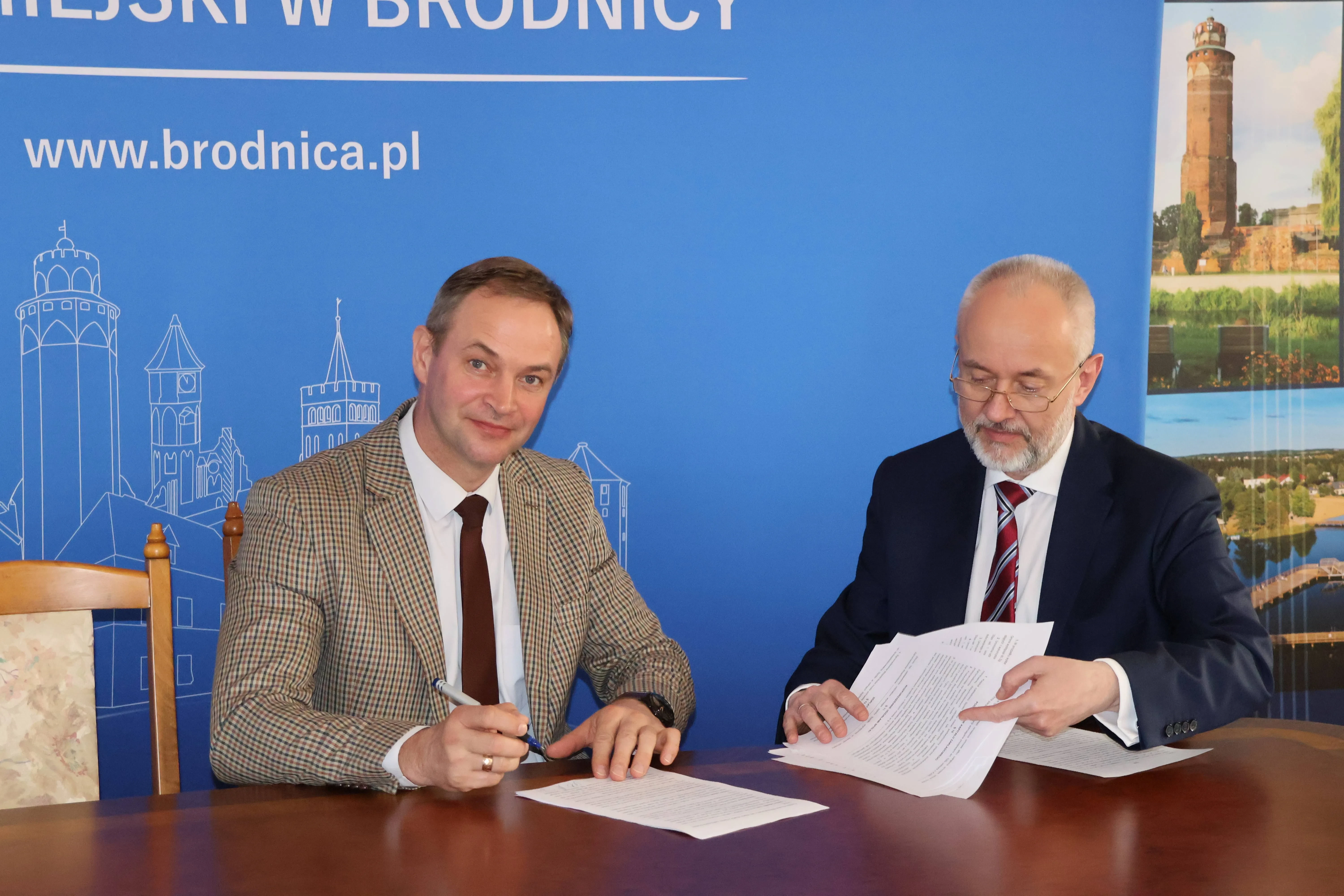 dwóch mężczyzn pokazuje podpisane dokumenty