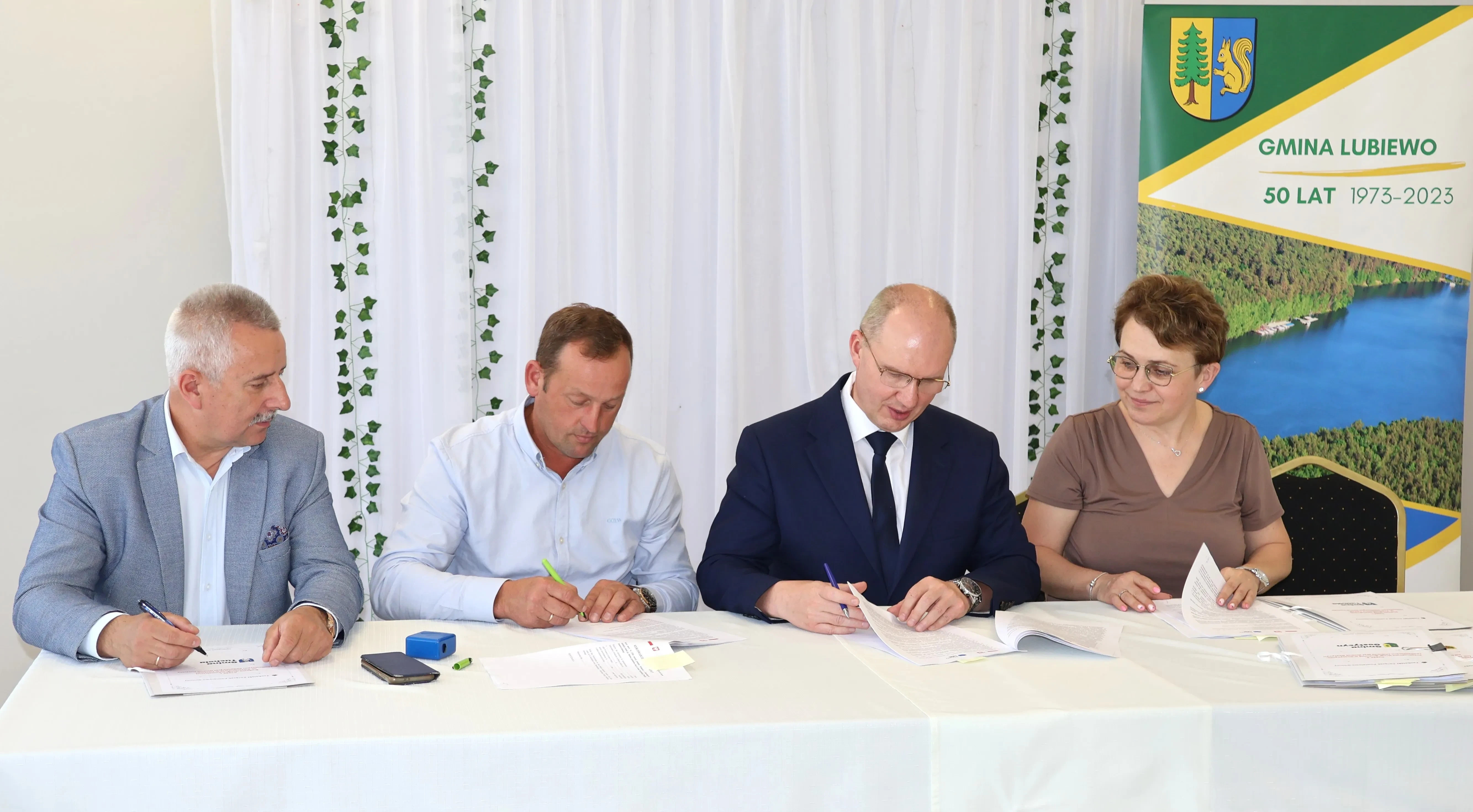 4 osoby przy podpisywaniu