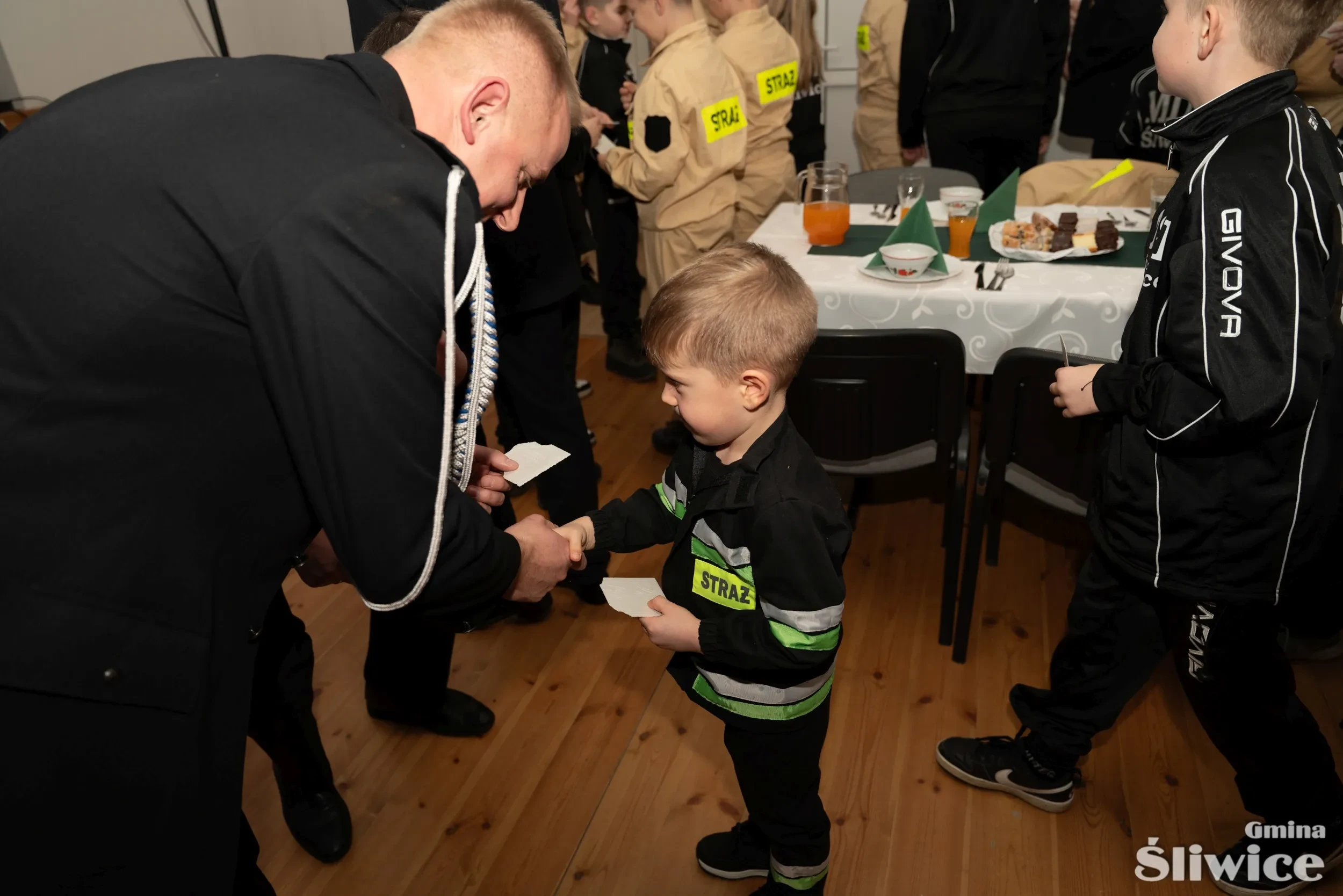 chłopiec w stroju strażaka dzieli się opłatkiem z mężczyzną