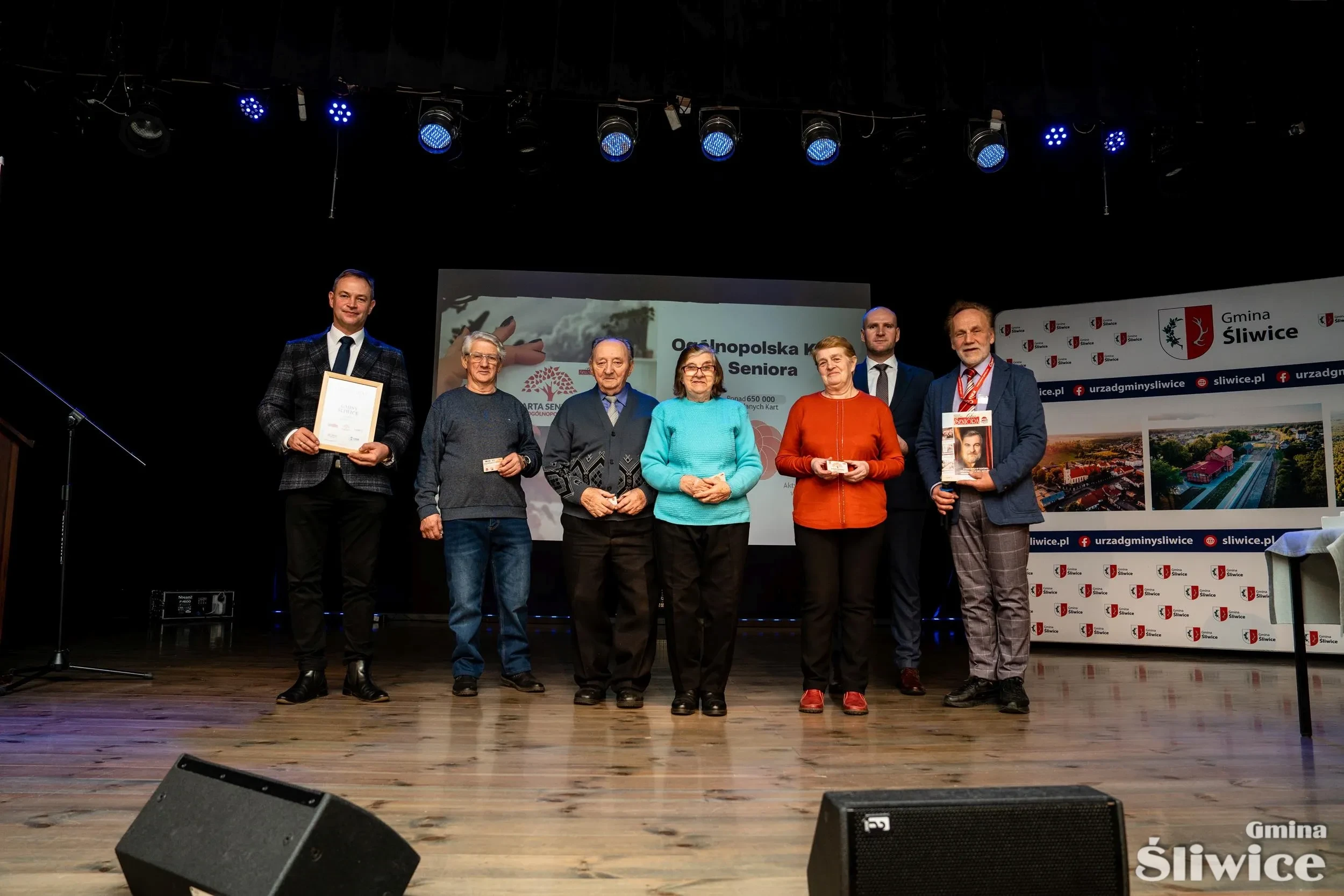 seniorzy z kartami na scenie