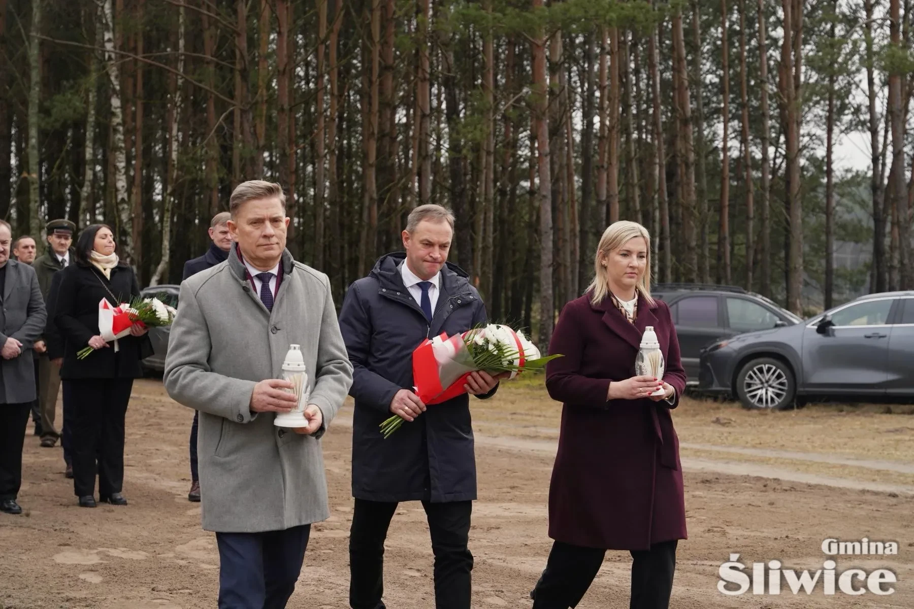 sekretarz, wójta i wicewójt trzymająca kwiaty i znicze