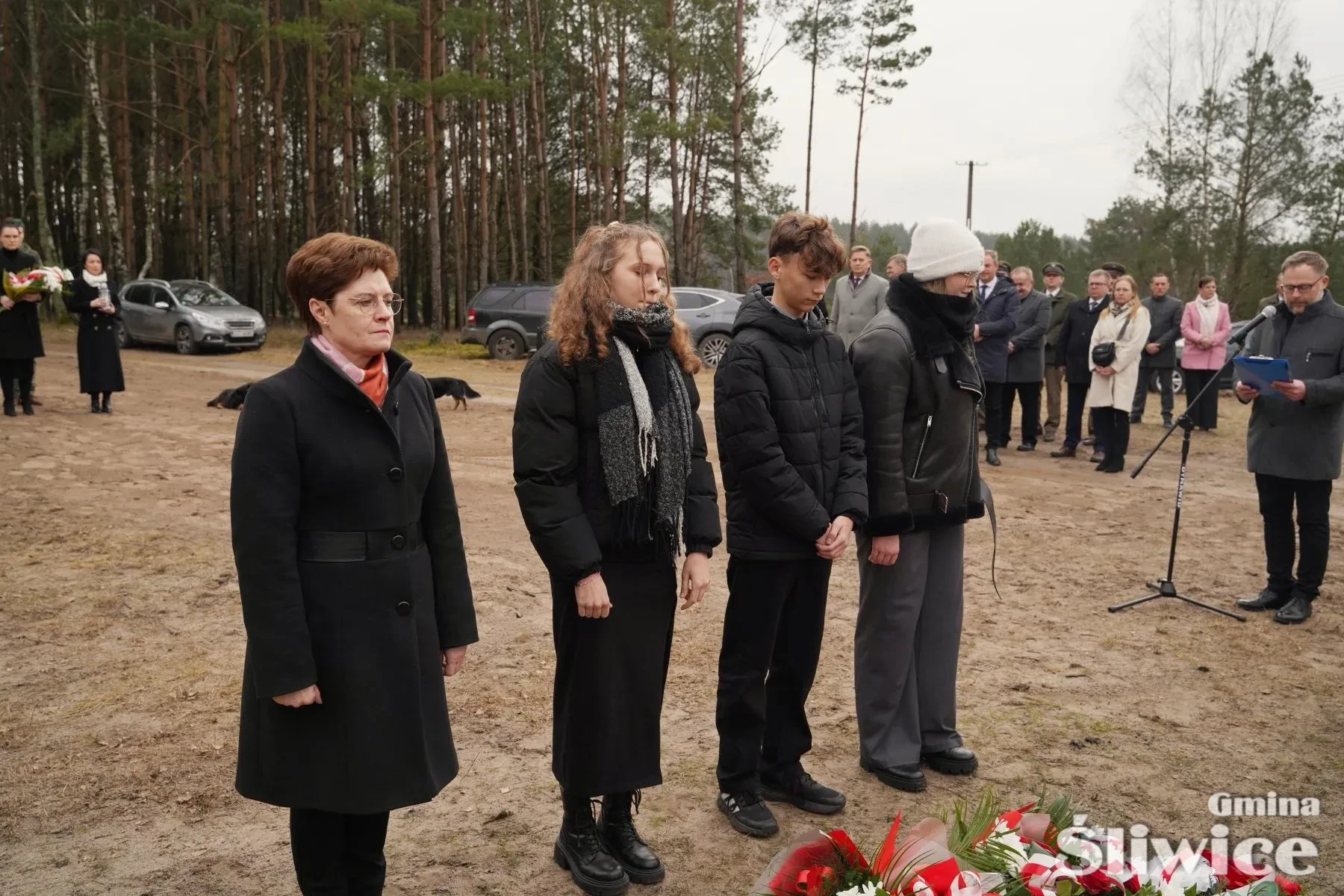 trójka dzieci stojąca przed leżącymi kwiatami