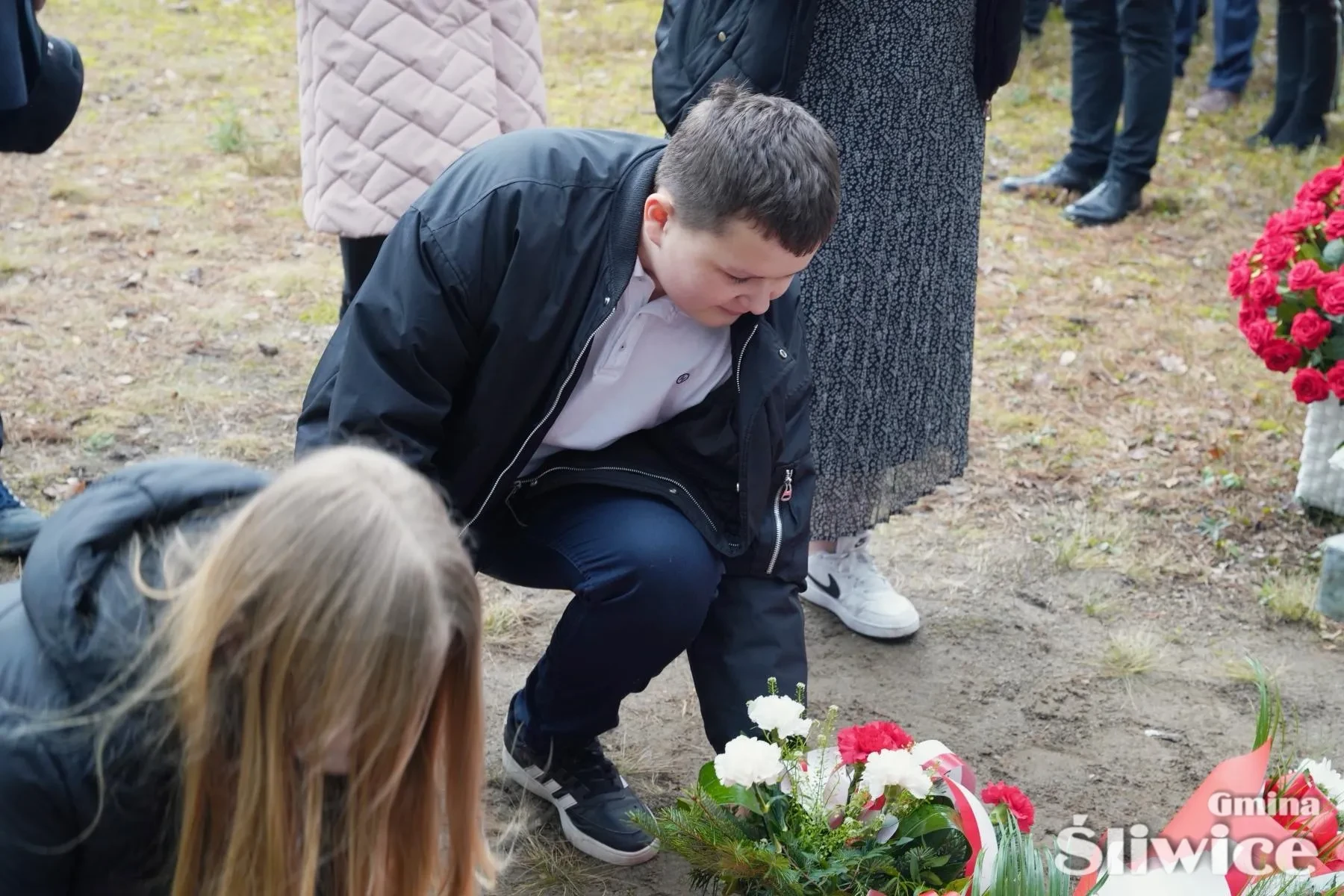 młody chłopiec kładzie kwiaty