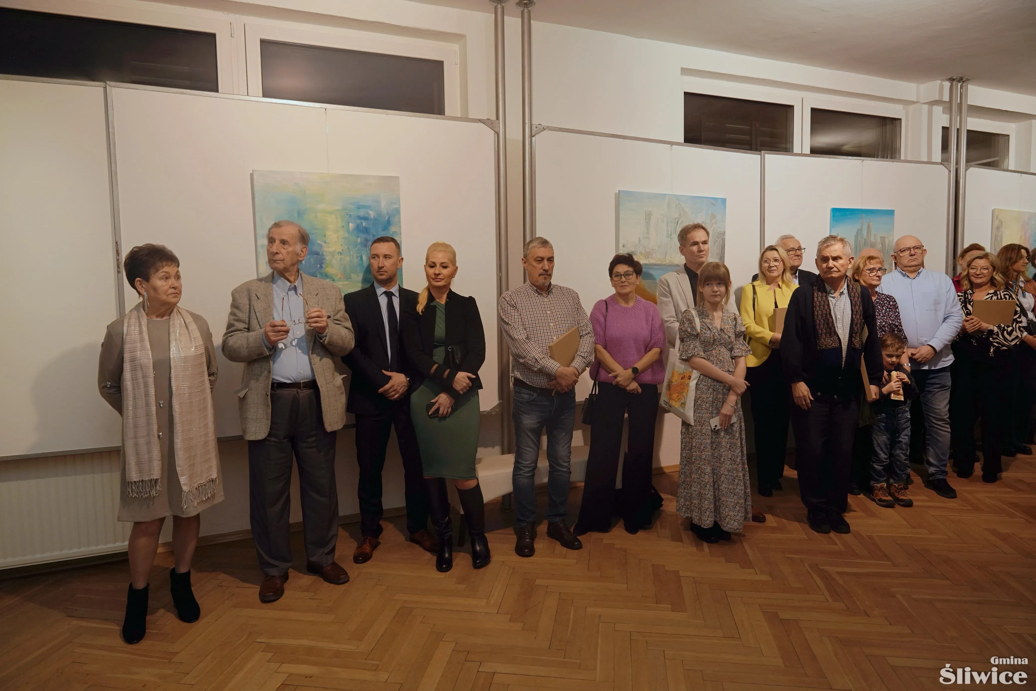 zgromadzone osoby stojące przy obrazach
