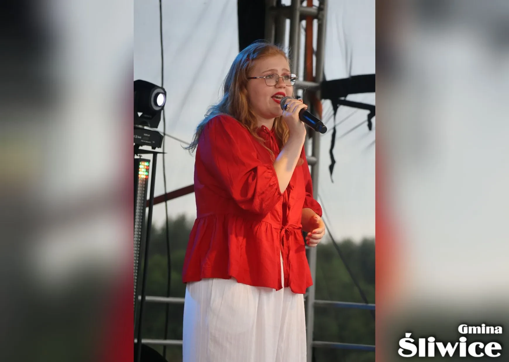 dziewczyna w czerwonej bluzce śpiewa na scenie