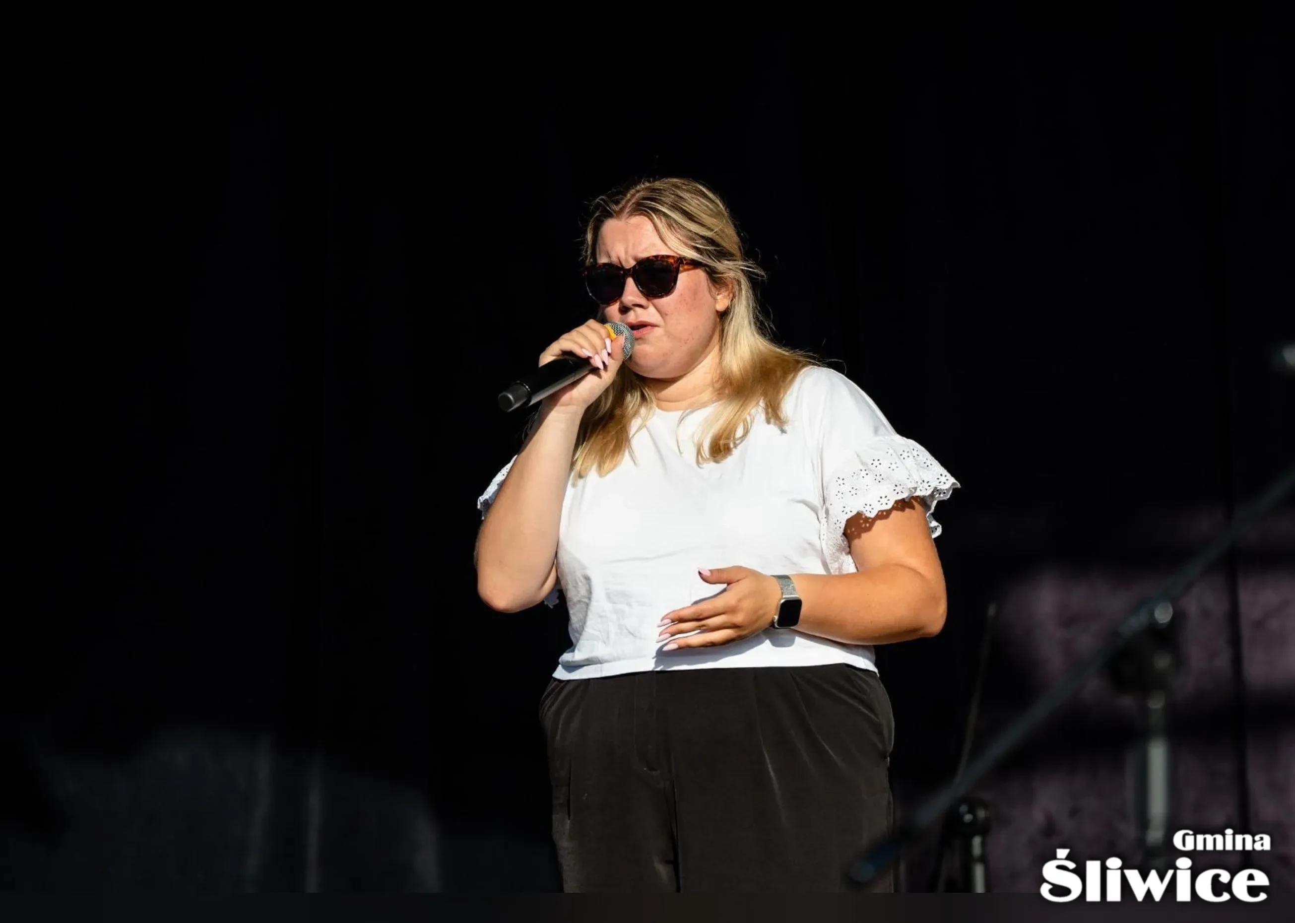 kobieta w okularach śpiewa na scenie