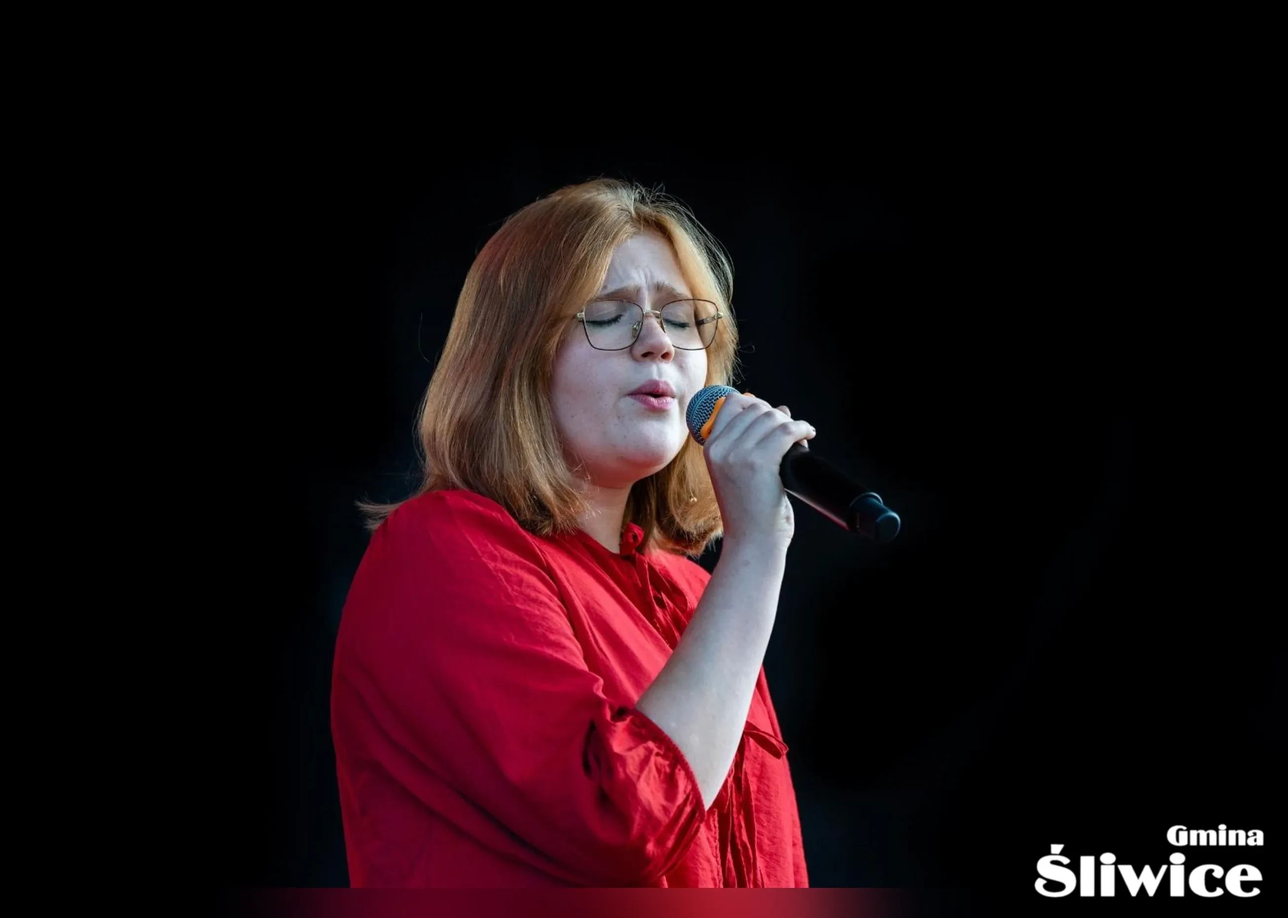 kobieta w rudych włosach śpiewa na scenie