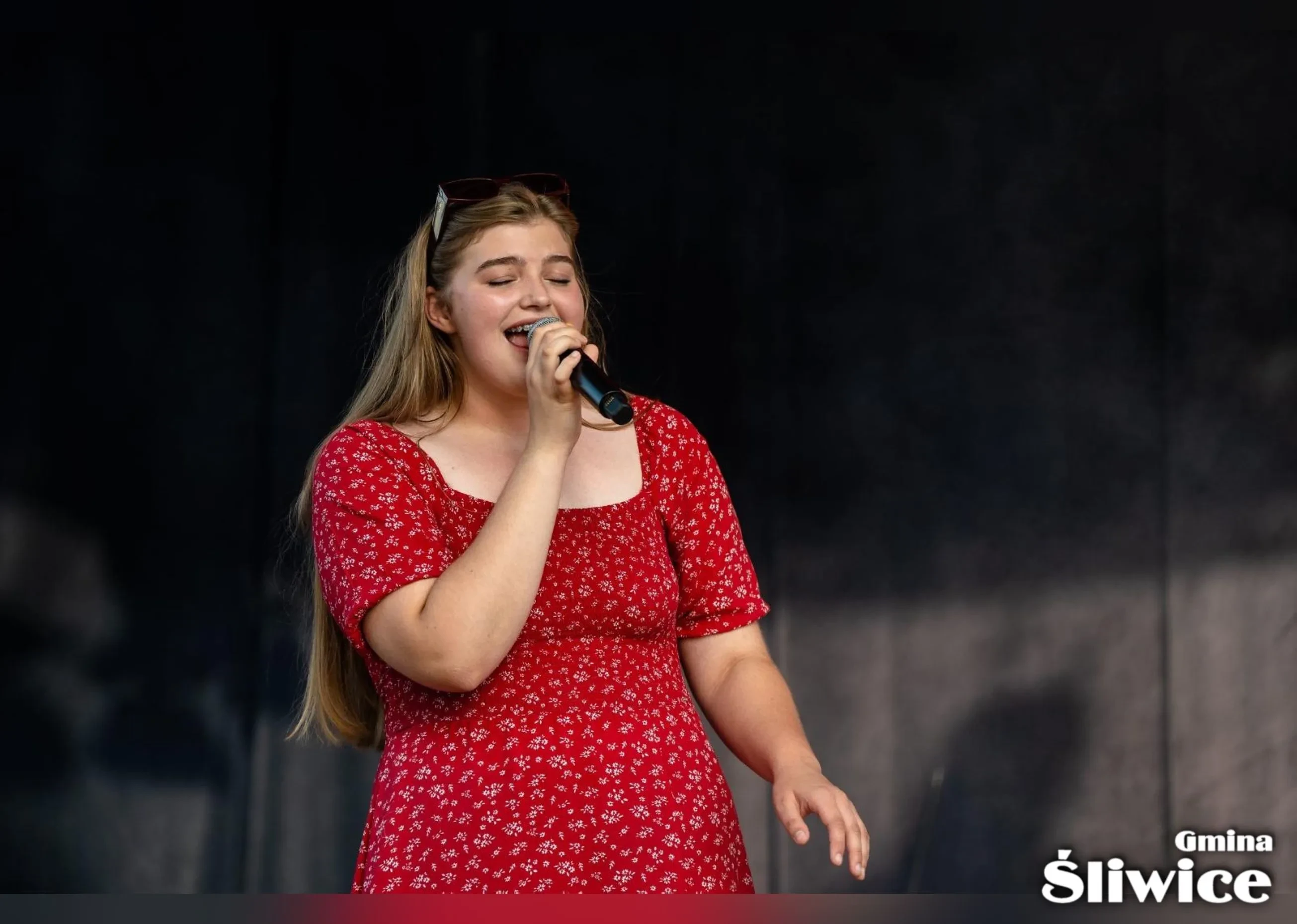kobieta w czerwonej sukience śpiewa na scenie