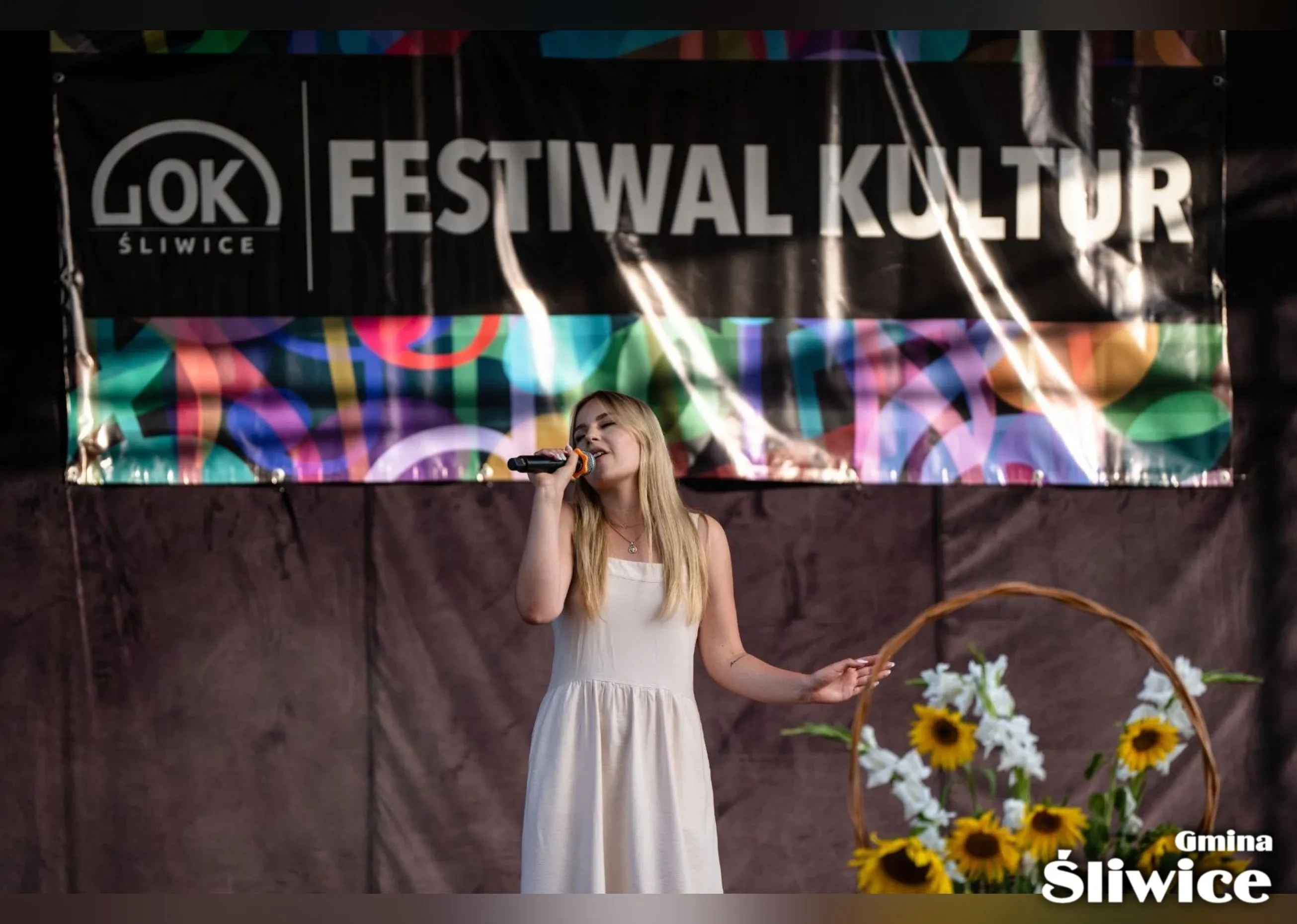 kobieta w jasnej sukience śpiewa na scenie