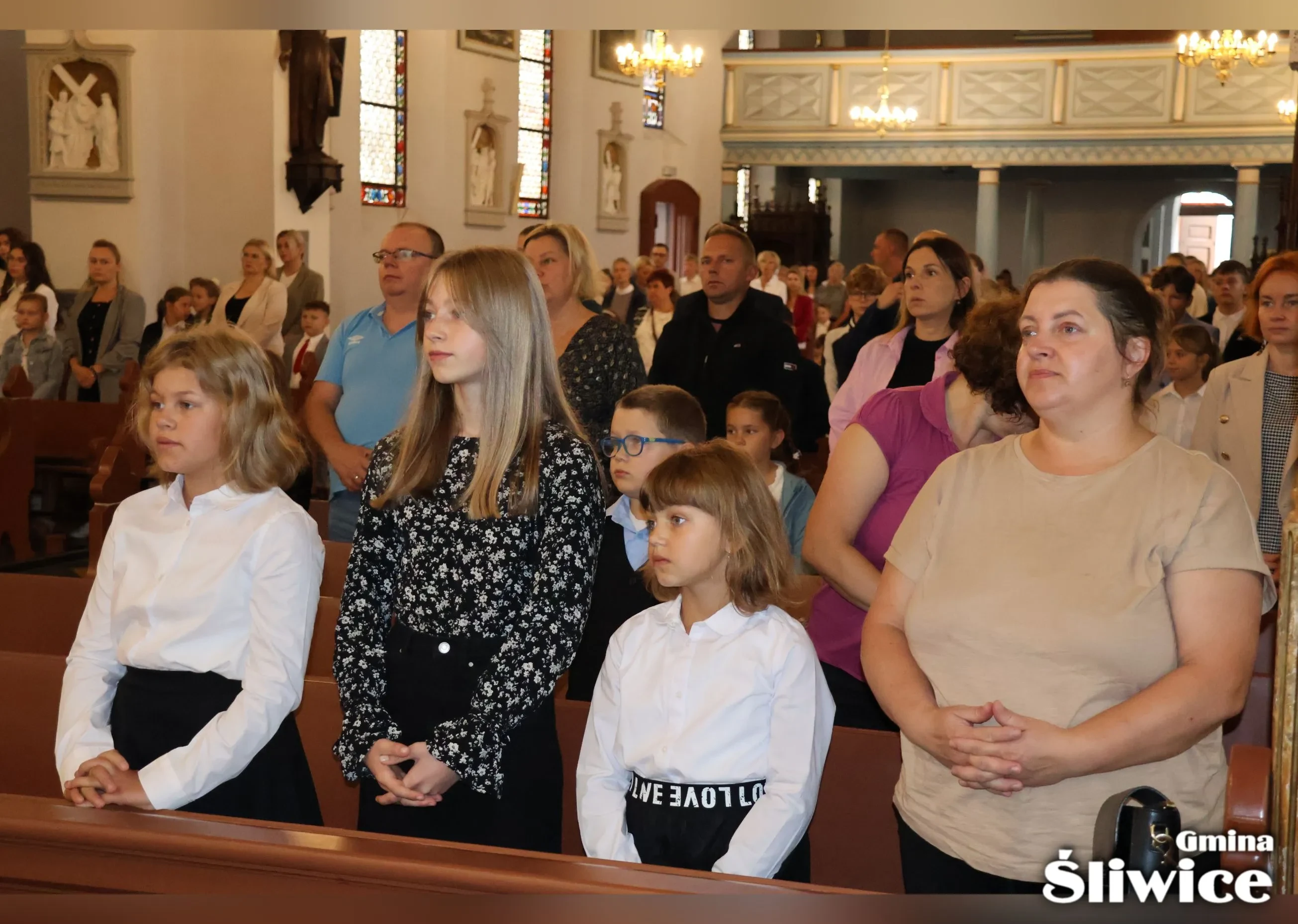 rodzice z dziećmi stoją w kościele