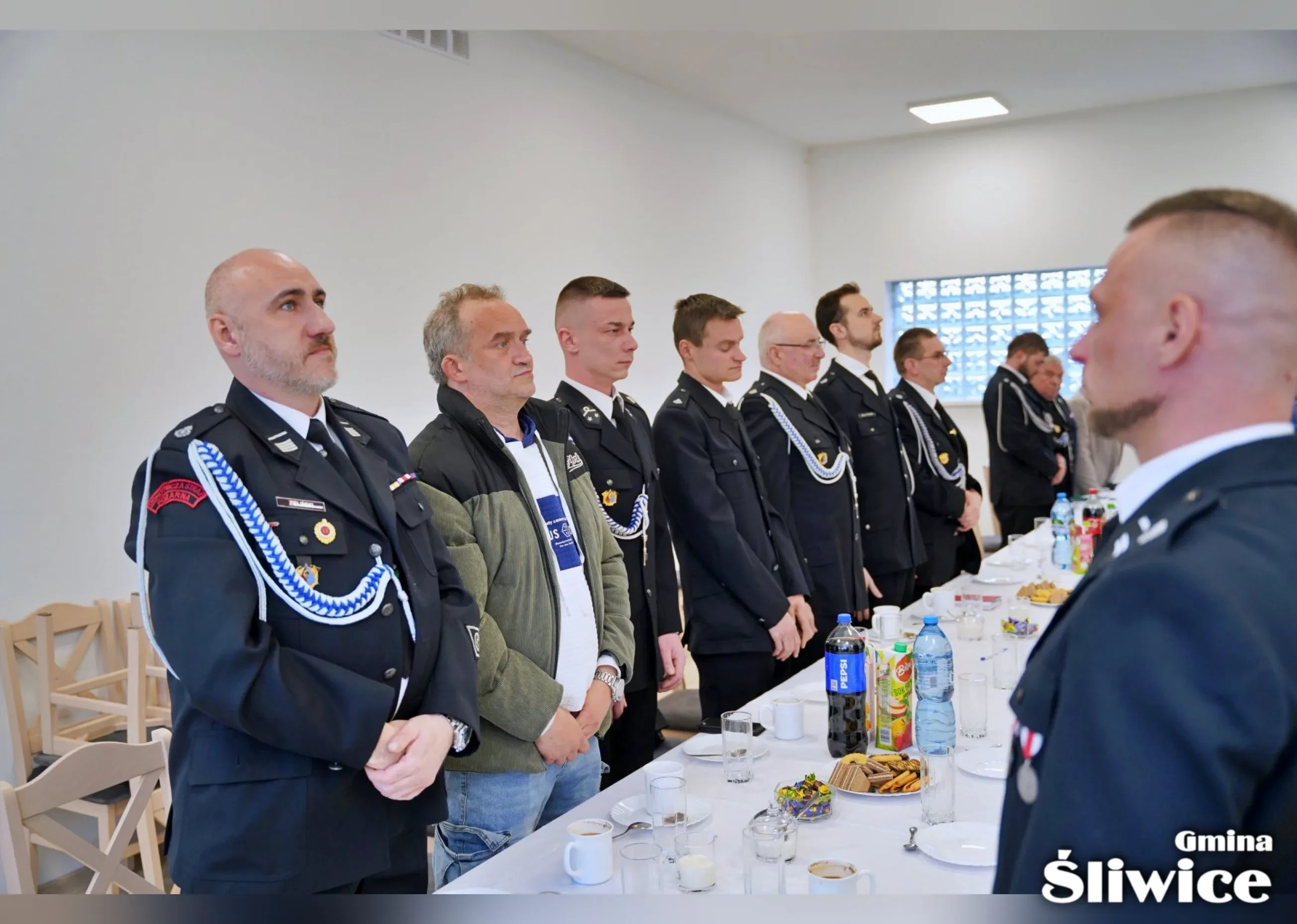 zebrani na sali stoją przy stołach