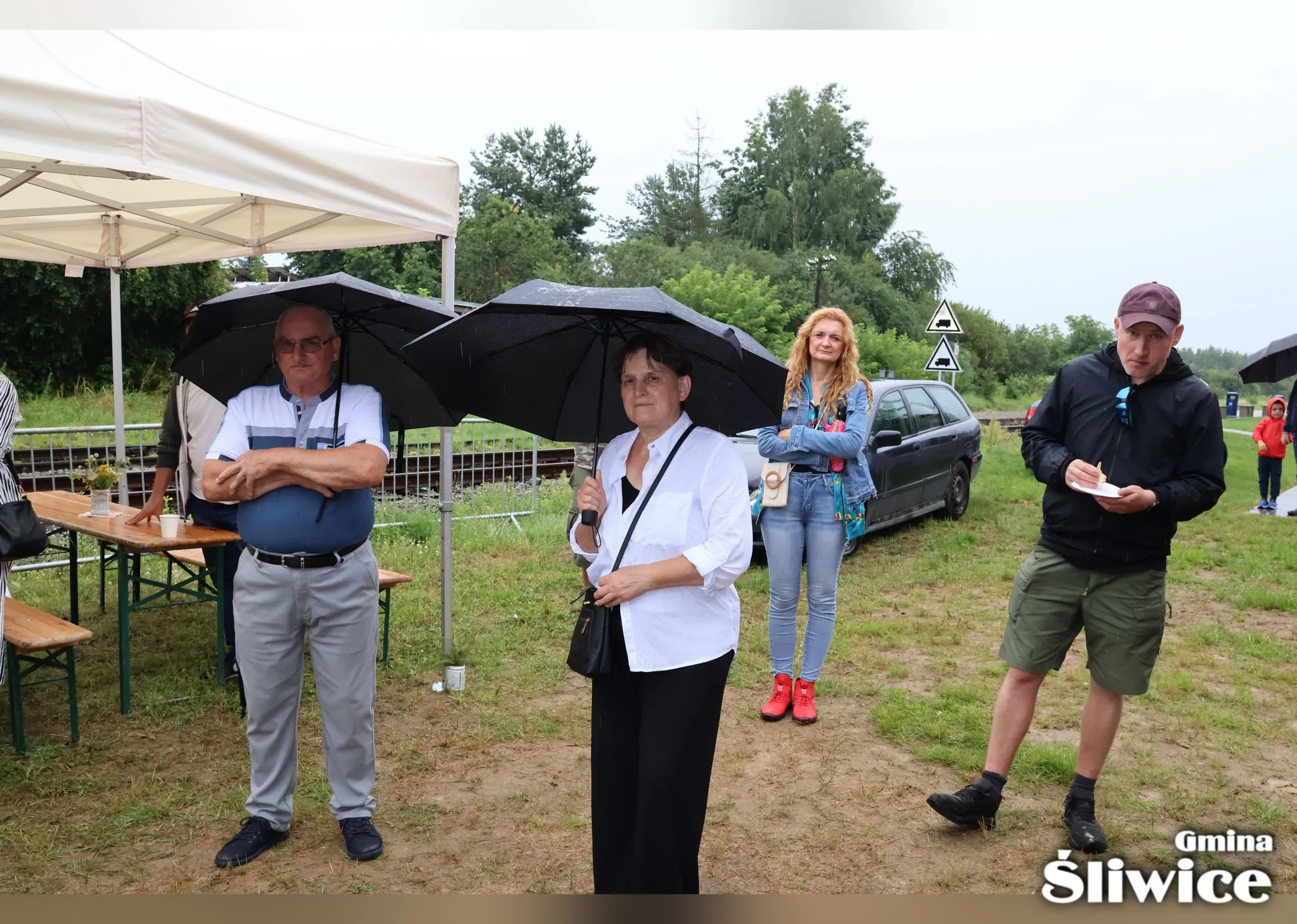 zebrani stoją pod parasolami i namiotami